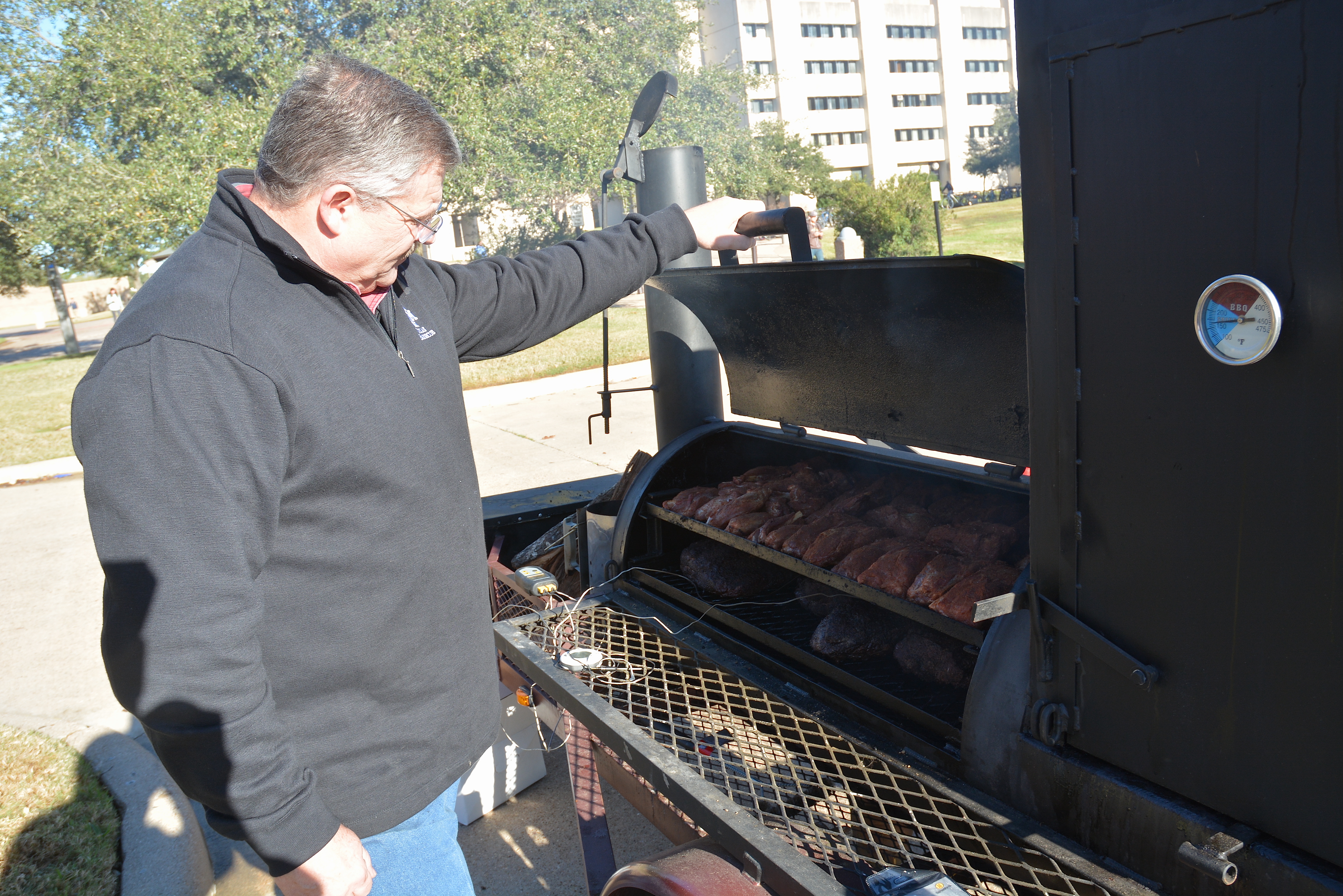Dr. Griffin checks the meat on a barbecue pit.