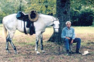 Local horse breeder and Texas A&M University professor emeritus Nat Kieffer sits with his 21-year-old former racing horse Nantachie, now used for trail riding.