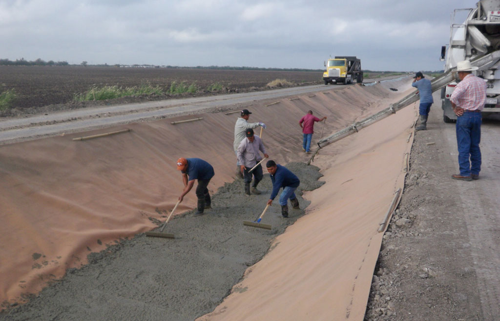 Workers in Hidalgo County spread concrete over a synthetic canal liner made of polyester. (Texas AgriLife Extension Service photo by Askar Karimov)