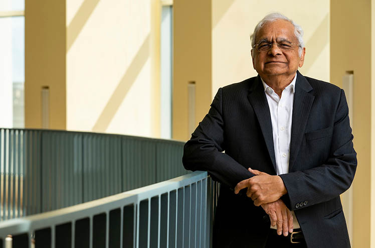 Dr. Dr. Girish Agarwal standing for a portrait with his arm resting on a handrail.