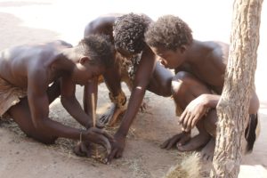 This is a group of young Himba men collaborating together to create a fire. 