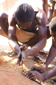 A Damara man shows us how they traditionally start fires. A small stick is moved quickly against a piece of wood to create sparks.