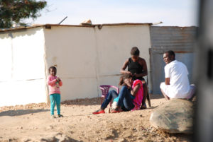 Four Namibians from Katatura standing around or having their hair braided. These people represent the everyday lives of the people who live in Katatura who can’t afford to live in the cities or are trying to improve their lives.