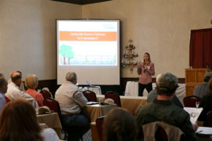 woman standing in front of conference room with presentation slide on big screen