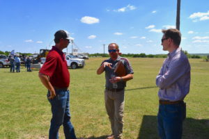 three men talking in field