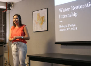 Makayla Faldyn near screen with Powerpoint presentation visible