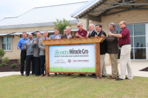 group of men by sign outside the new Scott'sMiracle-Gro Facility for Lawn and Garden Research.