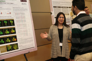 young woman talking by research poster