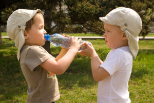 two boys drinking bottle of water