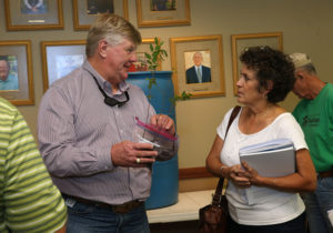 man holding tree seedling talking to a woman